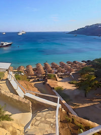 Stone steps leading down to a Mykonos beach with straw umbrellas and boats on the turquoise sea. Artwork by Rosalie Powell.