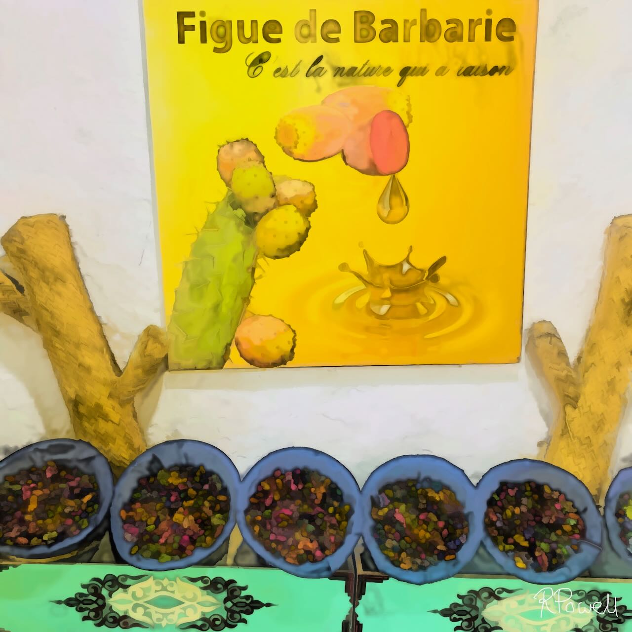 Painting of a Moroccan display showcasing prickly pear (figue de barbarie) products. A bright yellow sign with a cactus and dripping oil hangs above bowls filled with dark seeds, set on a green patterned cloth. Natural wood branches frame the scene, highlighting the organic and traditional feel. The following images show the same artwork displayed in different interior settings.