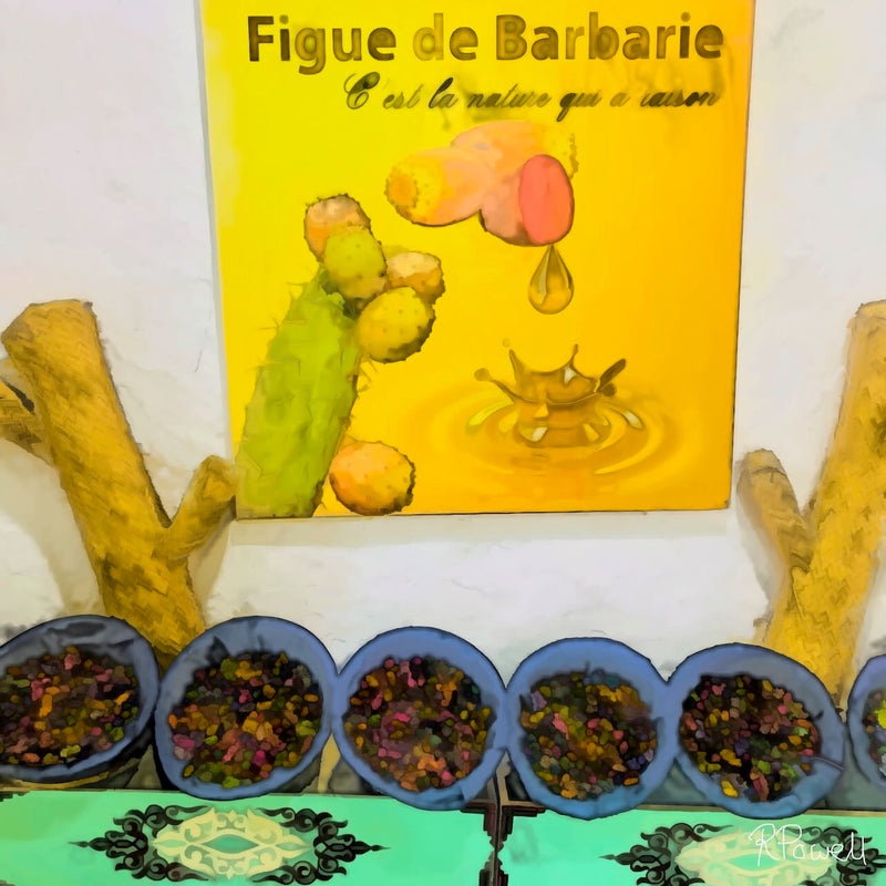 Painting of a Moroccan display showcasing prickly pear (figue de barbarie) products. A bright yellow sign with a cactus and dripping oil hangs above bowls filled with dark seeds, set on a green patterned cloth. Natural wood branches frame the scene, highlighting the organic and traditional feel. The following images show the same artwork displayed in different interior settings.