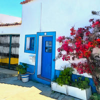 Painting of a small white house with a bright blue door and window frame, blooming red bougainvillea climbing the wall, and potted green plants by the entrance on a sunny Portuguese street. The following images show the same artwork displayed in different interior settings.